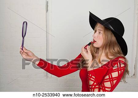 Blonde teenage girl holding a mirror and applying lipstick. View Large Photo Image Stock Image - Blonde teenage girl holding a mirror and applying lipstick.. Fotosearch