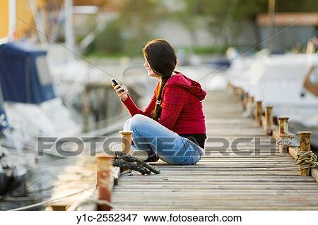 Stock Photo - Casual teen girl reading sms message on cellphone. Fotosearch