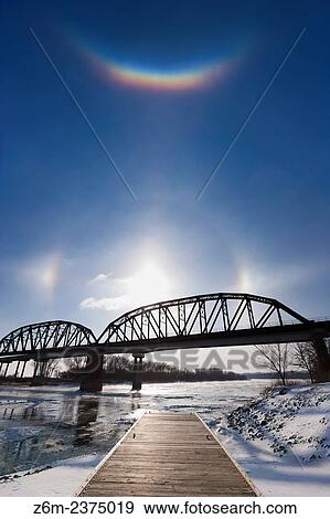 Stock Photo - Circumzenithal arc shines brightly above the sun and sun dogs along the Missouri River in eastern Nebraska on a bitter January day.. Fotosearch