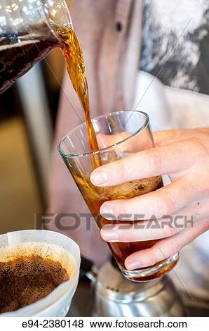 Stock Photo - Close up of a person pouring iced coffee into a glass.. Fotosearch
