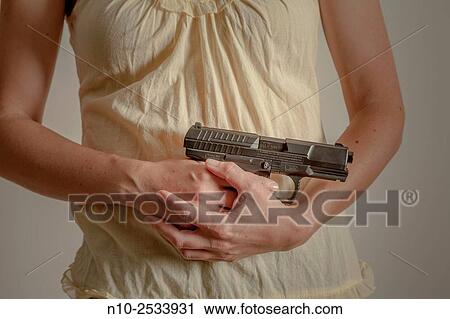 Close-up of a young woman holding a gun. View Large Photo Image Stock Image - Close-up of a young woman holding a gun.. Fotosearch