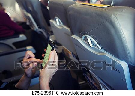 Closeup of hands of a young woman manipulating a mobile phone on an airplane View Large Photo Image Stock Image - Closeup of hands of a young woman manipulating a mobile phone on an airplane. Fotosearch