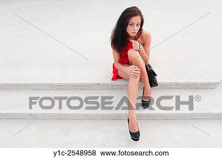 Stock Photo - Female teen in Red dress sitting low on steps.. Fotosearch