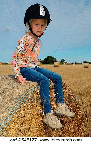 Stock Photo - Girl, 4 years, on a straw bale in Sweden.. Fotosearch