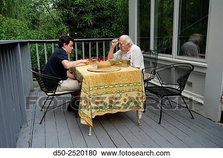Stock Image - Grandpa and grandson play chess on patio, Washington D. C., USA. Fotosearch