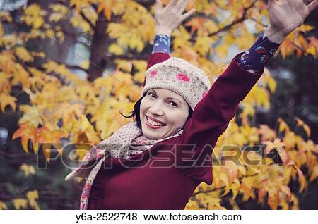 Stock Photo - Happy mid adult woman with raised arms, autumn. Fotosearch
