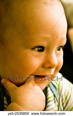 Stock Image - infant boy with a finger in his mouth.. Fotosearch