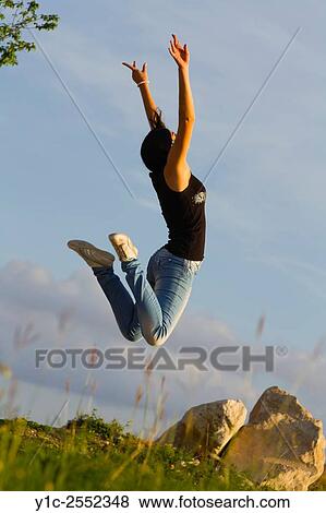 Stock Photo - Jump for joy girl next-door in denims. Fotosearch