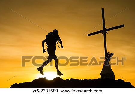 Stock Photo - Man with backpack mountain trail running on mountain overlooking Las Palmas city on Gran Canaria at sunrise. La Isleta, Las Palmas, Gran Canaria, Canary Islands, Spain.. Fotosearch