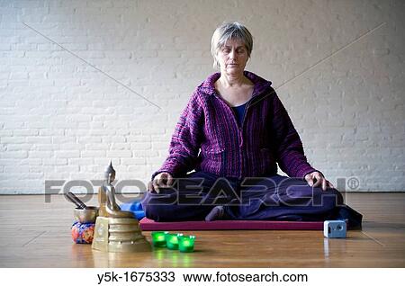 Older woman, meditating in an empty room, using Buddhist techniques. View Large Photo Image Stock Image - Older woman, meditating in an empty room, using Buddhist techniques.. Fotosearch