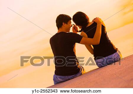 Stock Image - Playful teen couple before sunset horizon. Fotosearch