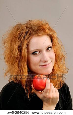 Stock Photograph - Redhaired young woman with a red apple.. Fotosearch