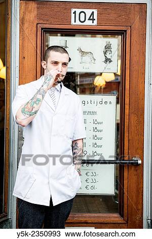 Rotterdam, Netherlands. Barber store Schorem. Portrait of a barber with tattoos on his arm, smoking a cigarette just outside the front door. View Large Photo Image Stock Image - Rotterdam, Netherlands. Barber store Schorem. Portrait of a barber with tattoos on his arm, smoking a cigarette just outside the front door.. Fotosearch