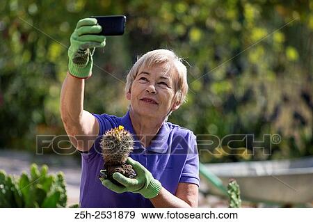 Stock Photo - Russian Federation. A pensioner in the garden with the phone.. Fotosearch