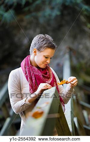 Stock Photo - Young lady is watching fallen leaf View Large Photo Image Stock Image - Stock Photo - Young lady is watching fallen leaf. Fotosearch