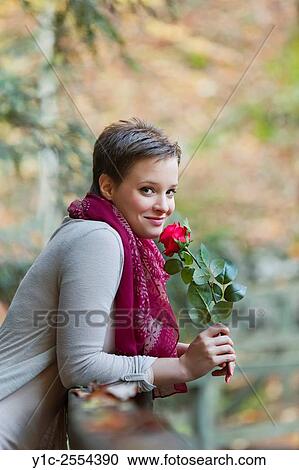 Stock Image - Stock Photo - Young woman with rose flower in hands. Fotosearch