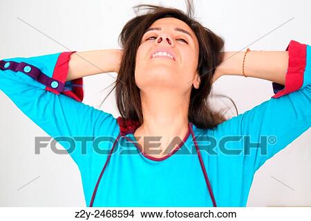 Picture - Stressed girl in blue pyjamas holding her hair and looking up.. Fotosearch