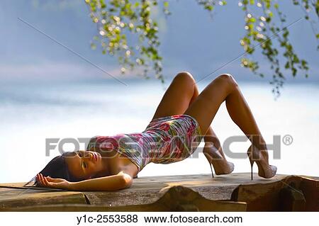 Stock Photo - Stretching atop wooden table slender young woman. Fotosearch