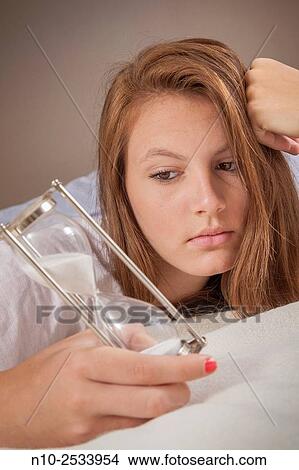 Teenage girl on her bed with an hourglass. View Large Photo Image Picture - Teenage girl on her bed with an hourglass.. Fotosearch