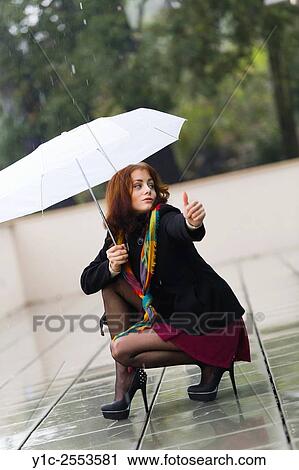 Stock Image - Teenager girl hitchhiking on rainy day. Fotosearch