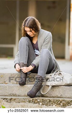 Stock Image - Teenager girl is tying boots. Fotosearch