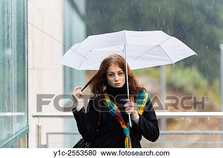 Stock Image - Teenager girl pulling hair umbrella in hand. Fotosearch