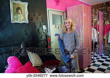 Stock Photo - The Hague, Netherlands. 54 year old classical ballet teacher in her colorful bedroom sorting out her wardrobe in front of wardrobe closets.. Fotosearch