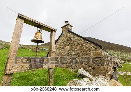 Stock Photo - The village bell and stone remains of the evacuated village on St. Kilda, declared a nature reserve in 1957, Hirta, St. Kilda Archipelago, Scotland.. Fotosearch