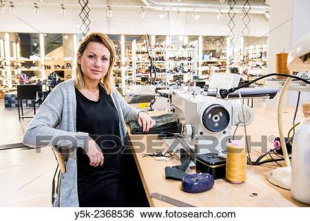 Tilburg, Netherlands. Young needlewoman buzzy shortening a jeans at her workstation in a fashion store for one of her customers. View Large Photo Image Stock Photograph - Tilburg, Netherlands. Young needlewoman buzzy shortening a jeans at her workstation in a fashion store for one of her customers.. Fotosearch