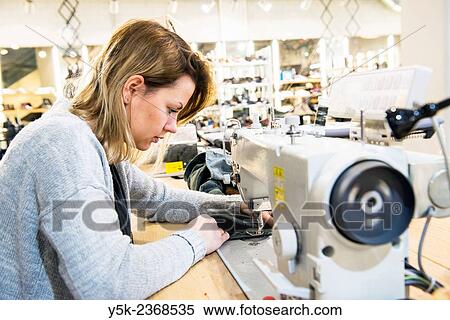 Tilburg, Netherlands. Young needlewoman buzzy shortening a jeans at her workstation in a fashion store for one of her customers. View Large Photo Image Stock Photography - Tilburg, Netherlands. Young needlewoman buzzy shortening a jeans at her workstation in a fashion store for one of her customers.. Fotosearch