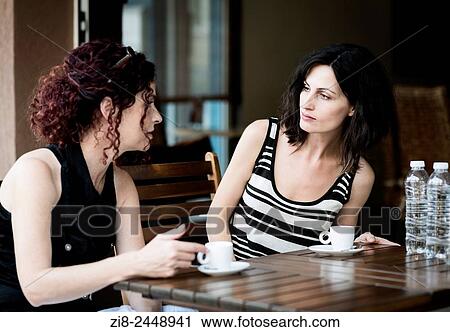 Stock Image - Two women chatting at a coffee shop.. Fotosearch