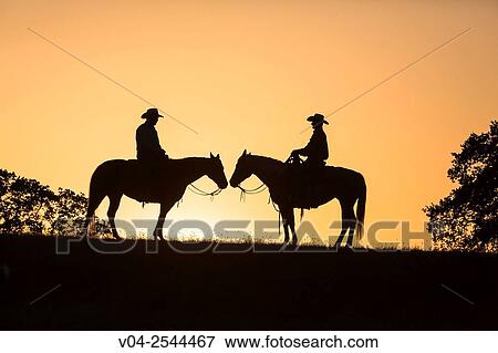 Stock Photo - Two wranglers cowboys on horses at sunset, California, USA. Fotosearch