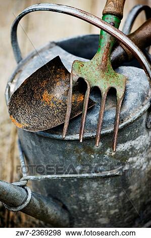 Vintage garden hand fork and trowel resting on weathered metal watering can. View Large Photo Image Stock Photo - Vintage garden hand fork and trowel resting on weathered metal watering can.. Fotosearch