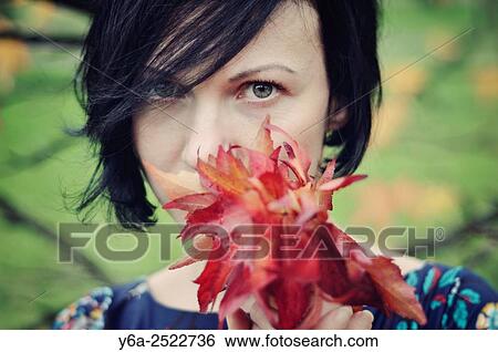 Stock Photograph - Woman holding leaves close to her face.. Fotosearch