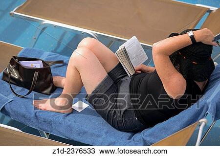 Stock Image - woman reading a book on board cruise liner.. Fotosearch