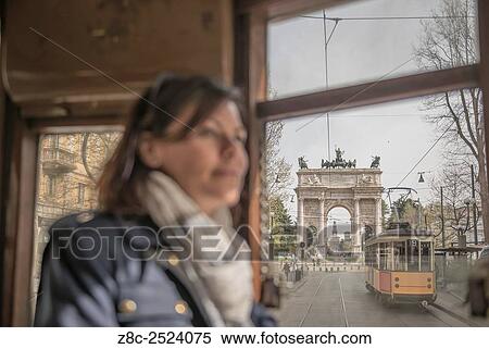 Stock Photography - Woman travel in a tram and in background Arco della pace and castle Sforza in Milan, Italy.. Fotosearch