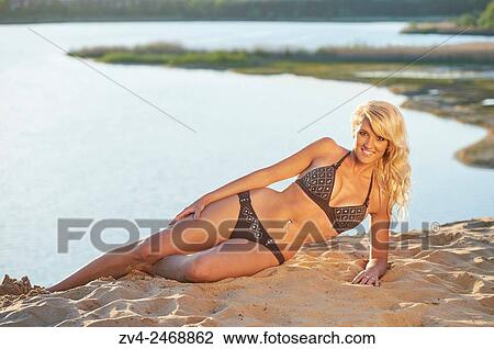 Young blond woman lying on a sandy beach in summer. View Large Photo Image Stock Image - Young blond woman lying on a sandy beach in summer.. Fotosearch