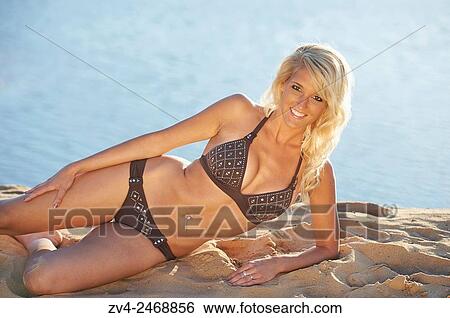 Young blond woman lying on a sandy beach in summer. View Large Photo Image Stock Photograph - Young blond woman lying on a sandy beach in summer.. Fotosearch