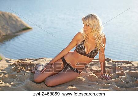 Young blond woman sitting on a sandy beach in summer. View Large Photo Image Stock Photo - Young blond woman sitting on a sandy beach in summer.. Fotosearch