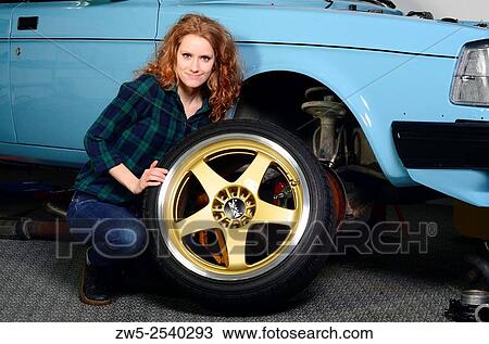 Stock Image - Young redhaired woman works in a garage in Ystad, Sweden.. Fotosearch