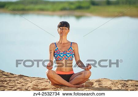 Young woman doing yoga on a beach next to a little lake. View Large Photo Image Picture - Young woman doing yoga on a beach next to a little lake.. Fotosearch