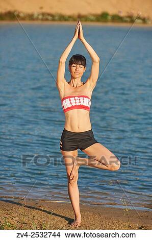 Young woman doing yoga on a beach next to a little lake. View Large Photo Image Picture - Young woman doing yoga on a beach next to a little lake.. Fotosearch