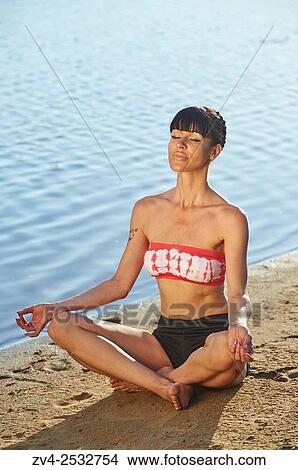 Young woman doing yoga on a beach next to a little lake. View Large Photo Image Picture - Young woman doing yoga on a beach next to a little lake.. Fotosearch