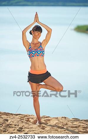 Young woman doing yoga on a beach next to a little lake. View Large Photo Image Stock Image - Young woman doing yoga on a beach next to a little lake.. Fotosearch