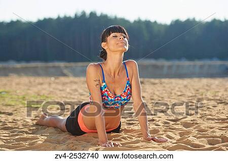 Young woman doing yoga on a beach next to a little lake. View Large Photo Image Stock Image - Young woman doing yoga on a beach next to a little lake.. Fotosearch