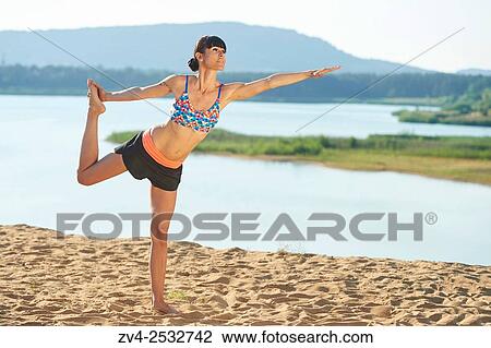 Young woman doing yoga on a beach next to a little lake. View Large Photo Image Stock Image - Young woman doing yoga on a beach next to a little lake.. Fotosearch