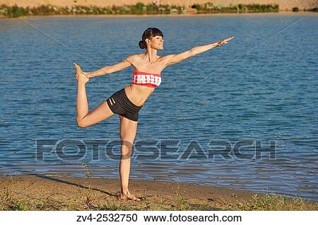 Young woman doing yoga on a beach next to a little lake. View Large Photo Image Stock Image - Young woman doing yoga on a beach next to a little lake.. Fotosearch