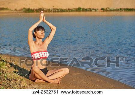 Young woman doing yoga on a beach next to a little lake. View Large Photo Image Stock Image - Young woman doing yoga on a beach next to a little lake.. Fotosearch