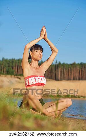 Young woman doing yoga on a beach next to a little lake. View Large Photo Image Stock Image - Young woman doing yoga on a beach next to a little lake.. Fotosearch
