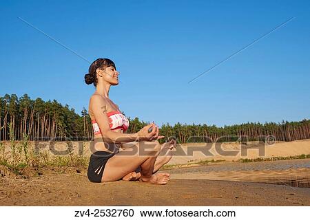 Young woman doing yoga on a beach next to a little lake. View Large Photo Image Stock Image - Young woman doing yoga on a beach next to a little lake.. Fotosearch